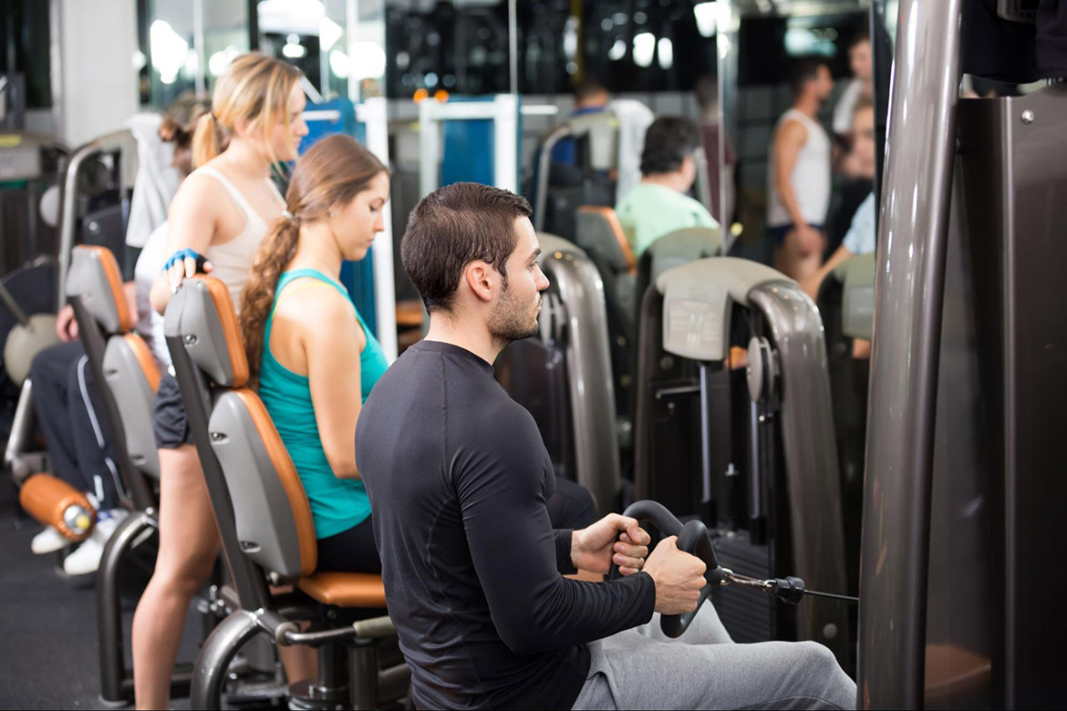 several people in gym using aerobic exercise machines