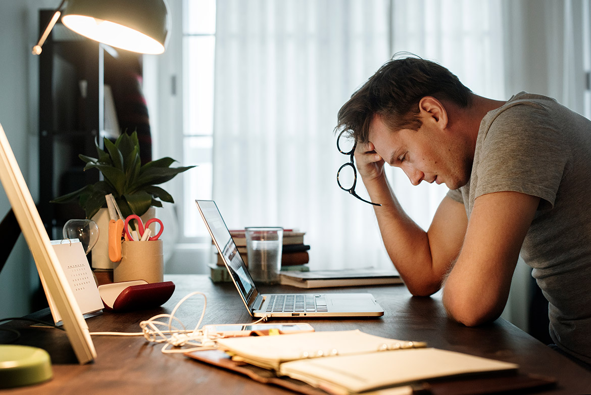 man stressed while working on laptop at desk